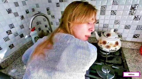 Blonde MILF bending over in striped sweater near teapot in kitchen