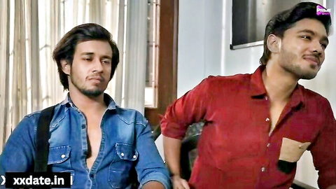 Two young Indian men in casual open denim jacket and red shirt posing intimately