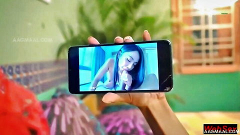 Hand holds phone screen showing nude Indian woman spreading shaved pussy lips wide open
