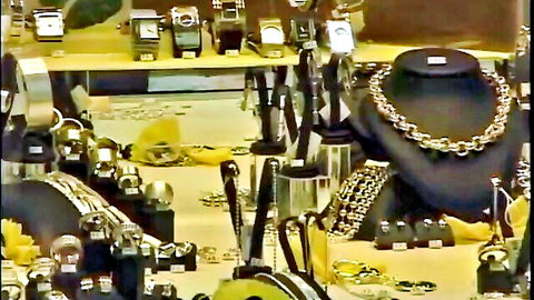 Shiny gold watches and thick chain necklaces displayed on black stands in cluttered jewelry stall