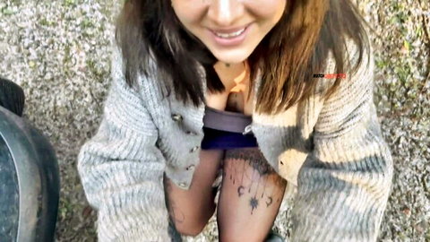 Arya LaRoca smiling with open cardigan showing cleavage and hiked skirt revealing tattooed thighs