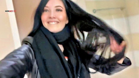 SugarLina smiling in black leather jacket and scarf, teasing selfie