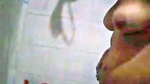 Close-up of mature Latina woman with large breasts in tiled bathroom