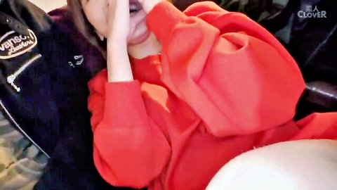 Asian woman in red oversized sweater covering mouth teasingly with man nearby