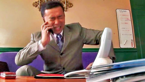 Excited Asian businessman in suit on phone in office