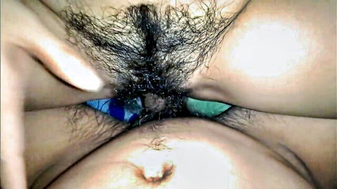 Closeup of hairy wet pussy with blue-green dildo inserted between spread labia
