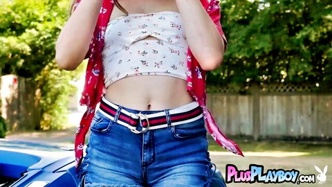 Playful babe in open floral kimono and tight ripped denim shorts teases outdoors by blue car