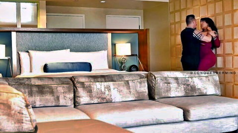 Brunette BBW in red dress intimately embraces man in hotel room