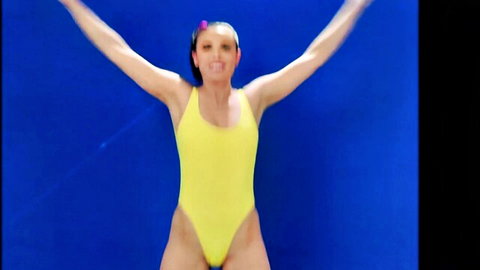 Calvert Day in tight yellow swimsuit, arms raised, athletic pose