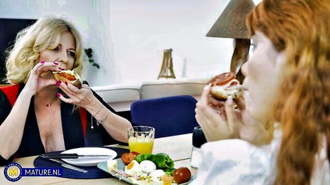 Mature blonde and redhead lesbians in low-cut tops sharing breakfast