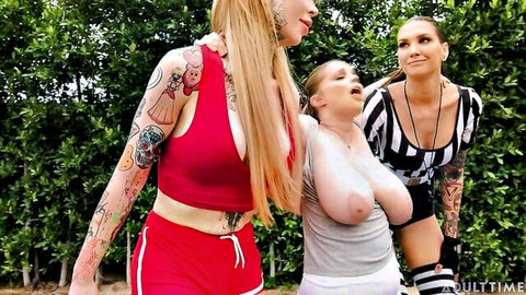 Tattooed blonde in red sportswear with busty friend and referee in outdoor TS threesome preview