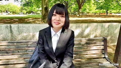 Smiling Japanese job-hunting student in black suit on park bench