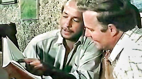 Vintage two men examining sexy photos in Color Climax hardcore scene