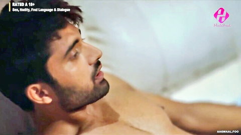Handsome bearded Indian man shirtless in bed, seductive side view