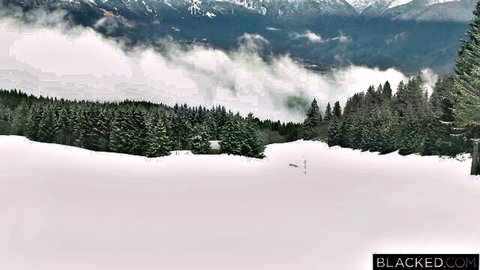 Snowy mountain landscape with pine forests and BLACKED.COM watermark, no visible action