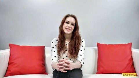 Freckled redhead smiling on Czech casting couch in polka dot top