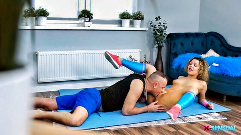 Muscular man licks shaved pussy and thighs of nude curly-haired woman in thigh-highs and sneakers on yoga mat