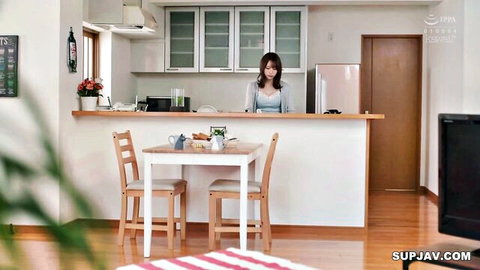 Busty Japanese woman in tight blue sweater smiling in kitchen