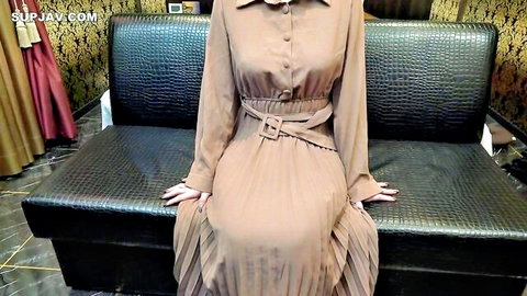 Cute smiling Asian woman in elegant beige dress sitting poised