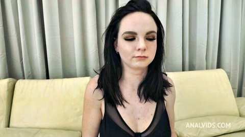 Freckled brunette with big tits and visible hard nipples in sheer black top sitting on couch