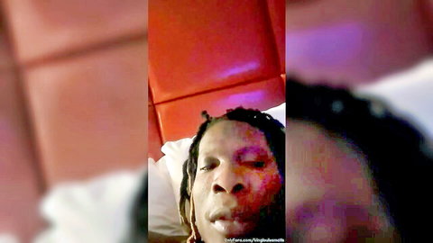 Close-up of sexy Black man with dreadlocks lying seductively on red bed pillow