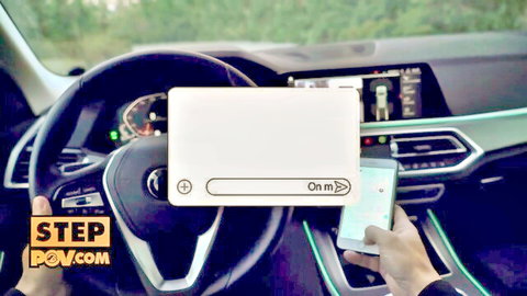 POV inside BMW car dashboard with hand holding phone showing 'On' message during encounter
