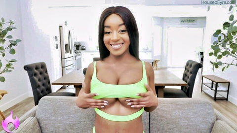 Ebony babe with huge tits squeezes massive breasts in neon green sling bikini smiling