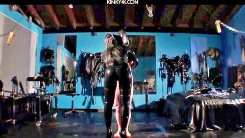 Curvy woman in shiny black latex catsuit posing in BDSM scene