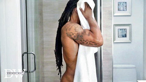Muscular ebony hunk with dreads covers cock with towel exposing firm black ass in bathroom