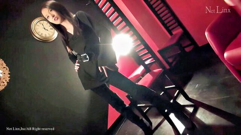 Seductive Japanese model in black blazer and thigh-high boots posing teasingly in red room