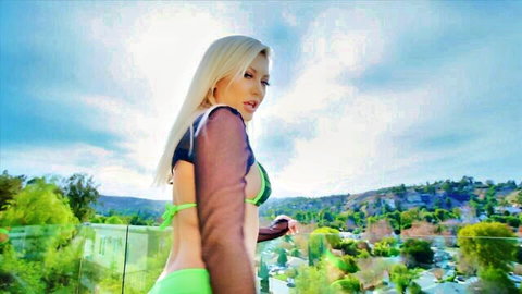 Blonde babe in sheer green bikini teases her ass on sunny balcony overlook