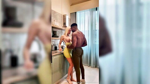 Skinny blonde with small tits in skimpy yellow dress embraced by muscular black stud in kitchen