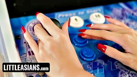 Asian babe's red-nailed hands gripping arcade joystick teasingly