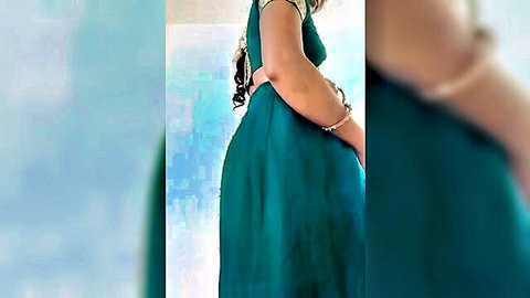 Curvy South Asian woman in tight emerald green dress posing sideways showing big ass curves
