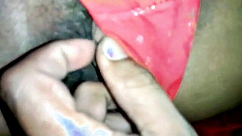 Close-up of wet naked pussy fingered by hand, red panties pulled aside