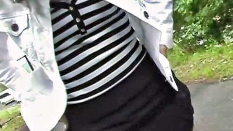 Asian woman in white jacket over striped polo shirt and black skirt posing outdoors