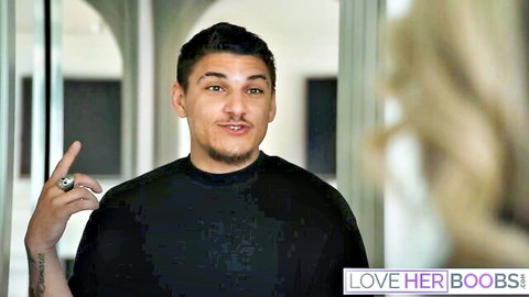 Latino stud gestures playfully at blonde babe's big boobs in intimate scene
