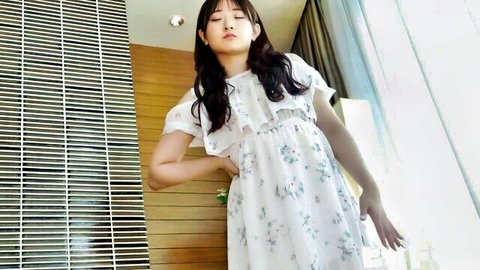 Young Asian woman in frilly floral dress posing in hotel room