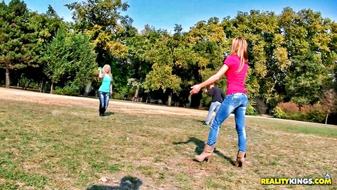 Alice Romain with blonde friend in jeans and heels outdoors, playful threesome tease