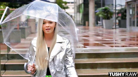 Kay Carter blonde bombshell in sexy silver jacket with umbrella in rainy outdoor tease
