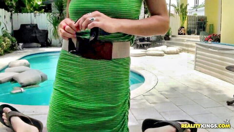 Brunette babe in tight green striped dress adjusting sunglasses by pool