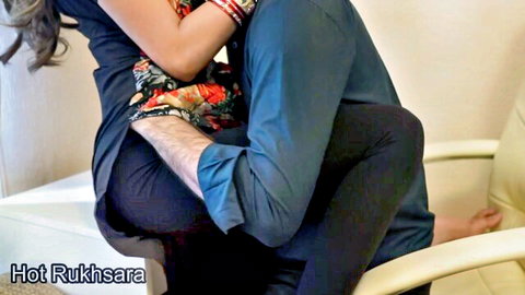 Sexy Indian brunette in floral saree sits on man's lap in intimate clothed embrace