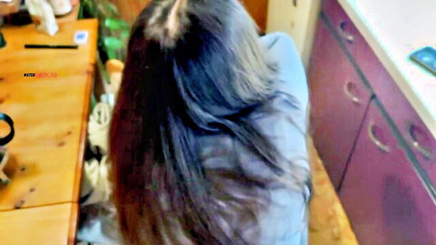 LeMaSnuSnu bent over in kitchen, long dark hair, blue top