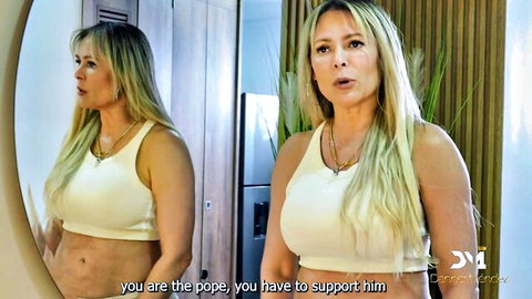 Blonde bombshell in tight white tank top poses in steamy mirror reflection showing cleavage and abs