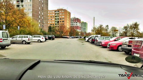 Car dashboard view of urban parking lot with cars and autumn apartment buildings
