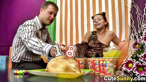 Skinny fair teen in leopard dress smiles as man cuts 18th birthday cake
