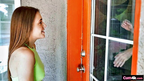 Smiling skinny brunette teen in green tank top as hand reaches through door window
