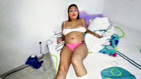 Curvy pregnant brunette in pink lingerie and socks posing seductively