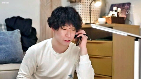 Young Asian man with curly hair talking on phone in white shirt
