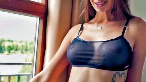 Seductive brunette in sheer black bra smiling by window